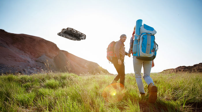 Hikers using HOVERAir X1 lightweight camera drone on a sunny outdoor trail.
