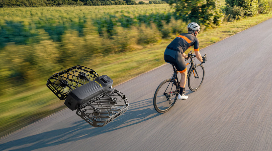 A cyclist in motion on a country road is autonomously tracked and filmed from behind by a HOVERAir flying camera.